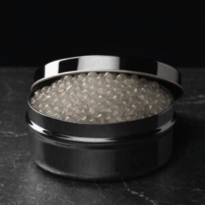 Open black caviar tin filled with large pale-grey Beluga pearls on dark stone